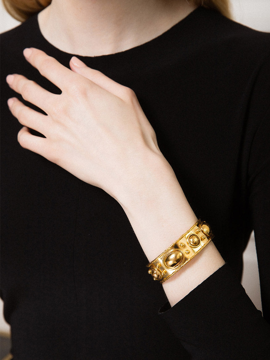 Person wearing a black long-sleeve top showcasing a Sylvia Toledano Bracelet Byzantin in Gold adorned with round and oval decorative elements.