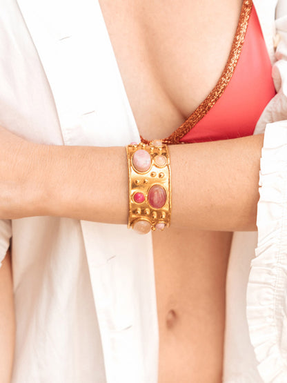 A person wearing a white shirt and a red bikini top sporting a Sylvia Toledano Cuff Byzantine in Pink Jade on their forearm.