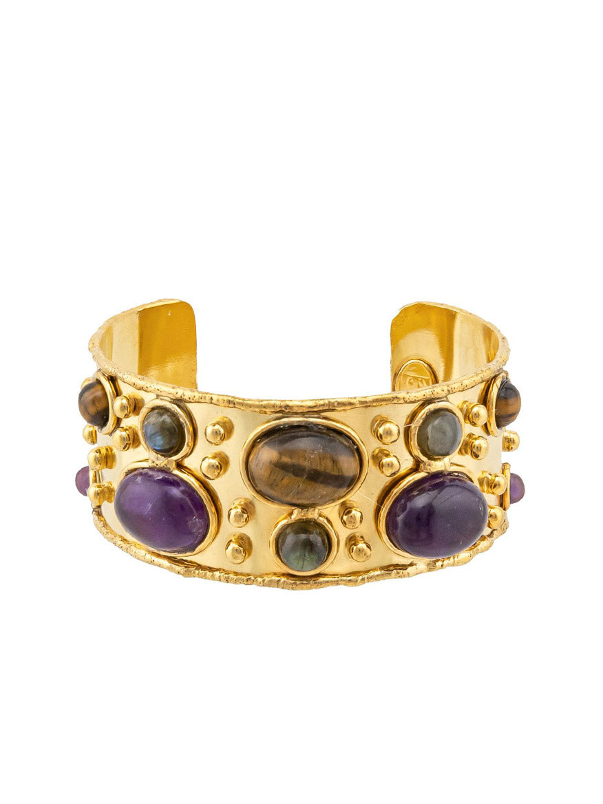 Sylvia Toledano's Cuff Byzantine features a gold cuff adorned with decorative bezel-set gemstones, including amethyst, tiger eye, and labradorite.