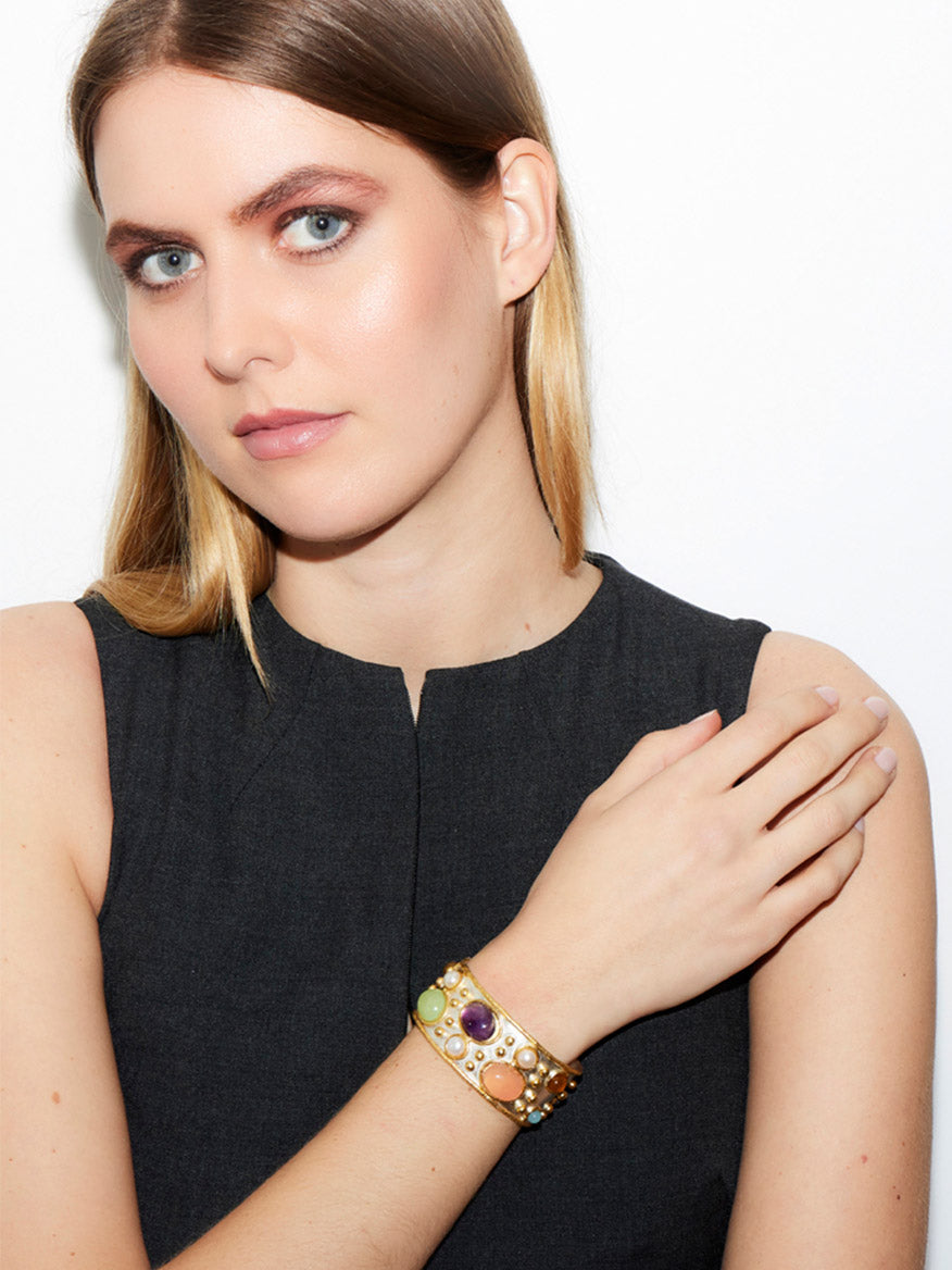 A woman with long hair is wearing a sleeveless black top and the Sylvia Toledano Cuff Byzantine, featuring amethyst stones, while posing gracefully against a white background.