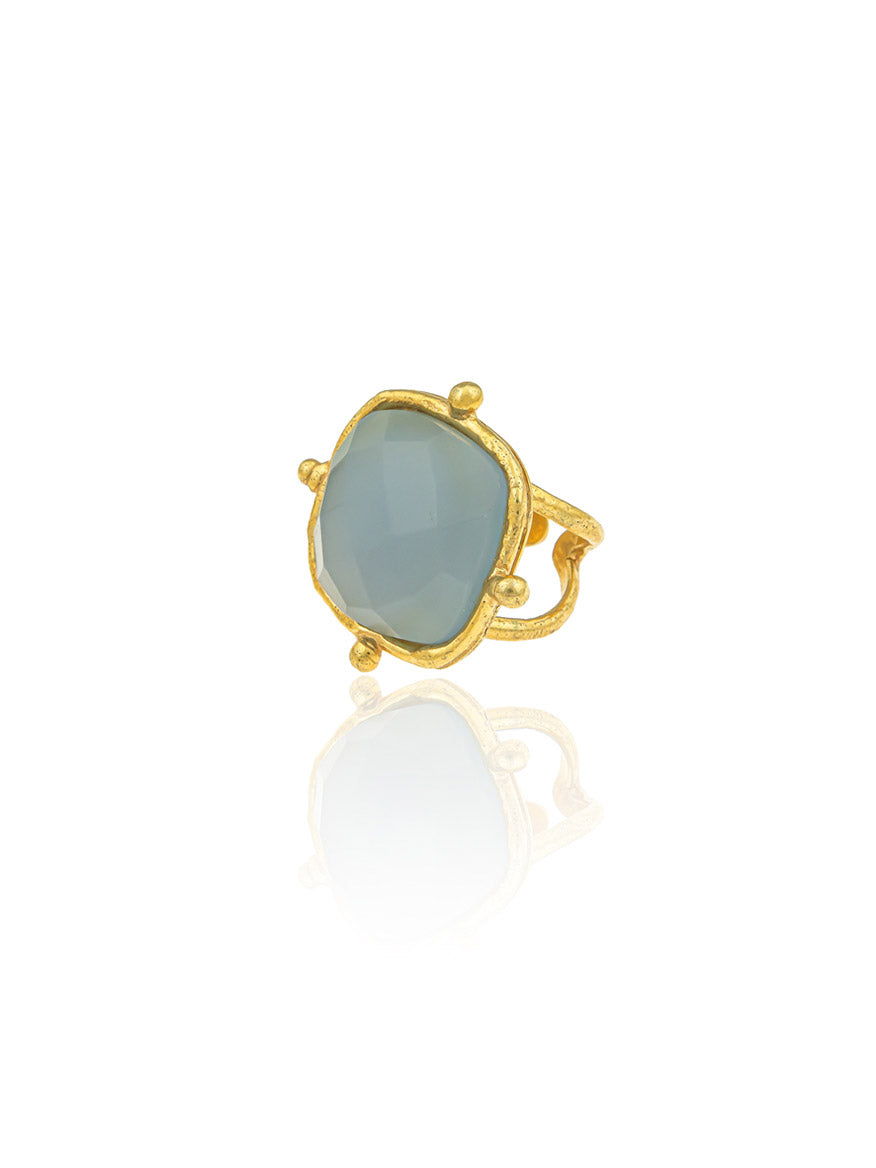 The Sylvia Toledano Ring Cushion showcases a striking, irregularly shaped, translucent blue Chalcedony stone set in fine gold.