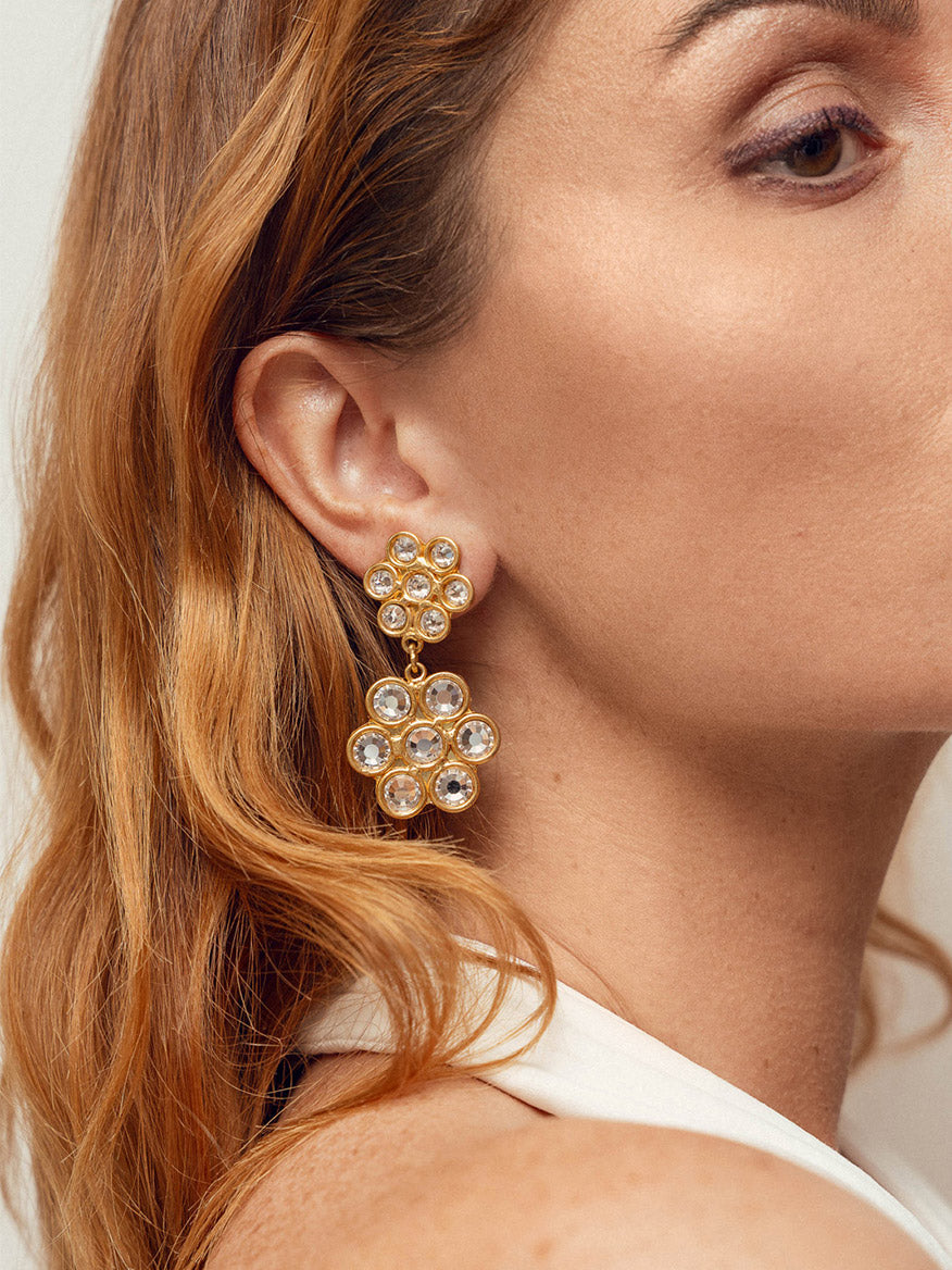 Close-up of a woman wearing large, gold, drop Sylvia Toledano Earrings Daisy in Gold & Swarovski Elements.