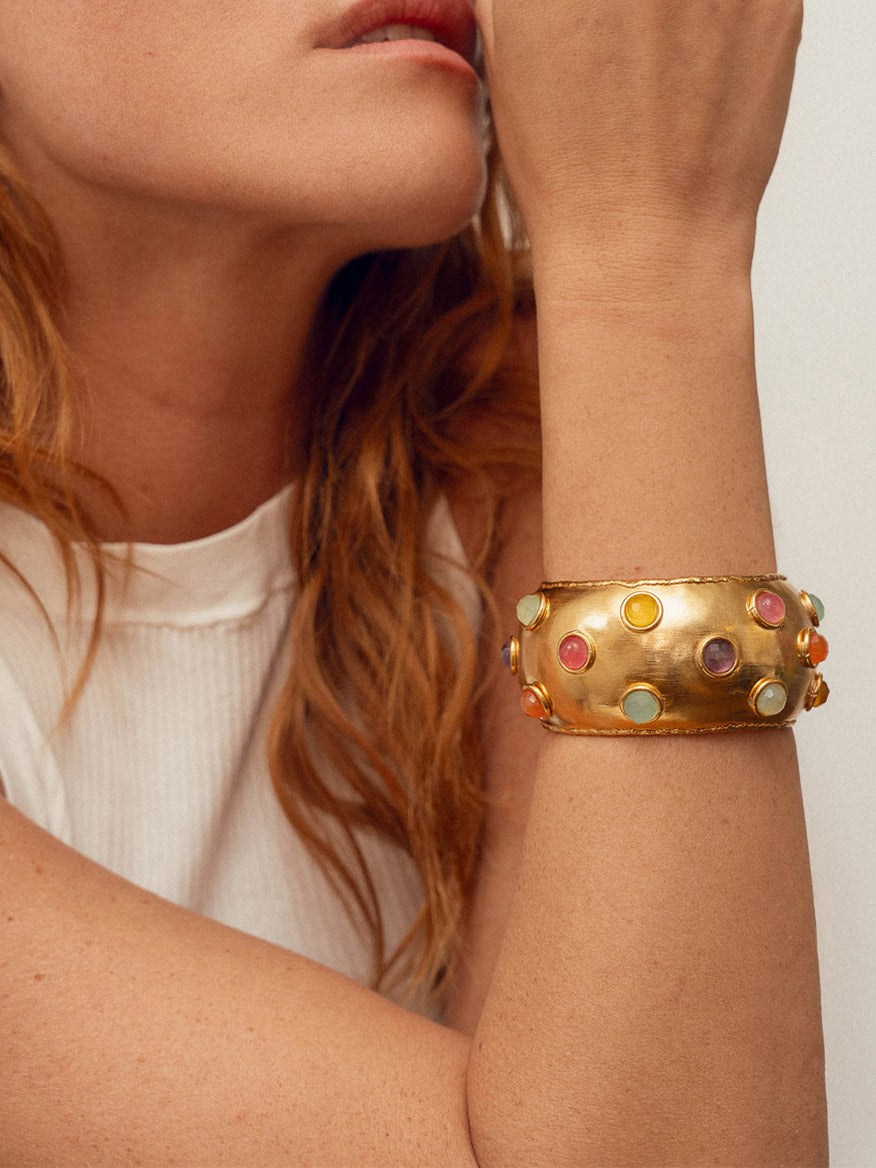 A woman with red hair leans on her hand, showcasing a chunky Sylvia Toledano Cuff Dune in Gold & Multi Summer adorned with fine gold and Multi Summer stones.