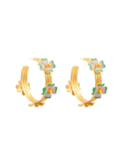 The Sylvia Toledano Earrings LuckyLove Hoops in Gold boast a brass base and gold finish, adorned with a floral design featuring green and pink accents.