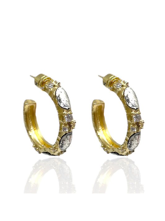 The Tat2 Designs Alma Hoops 1" in Gold & Vintage Silver feature gold hoops with silver oval accents, small clear gemstones, and distinctive textures inspired by the Tat2 Prince Collection.