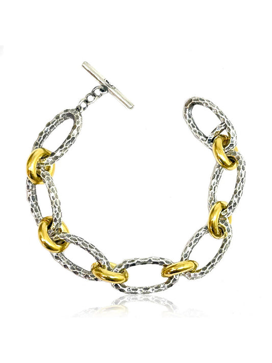 The Tat2 Designs Ravelle Hammered Chain Bracelet in Vintage Silver Two-Tone features modern shapes, custom metal textures, oval links, and a toggle clasp.