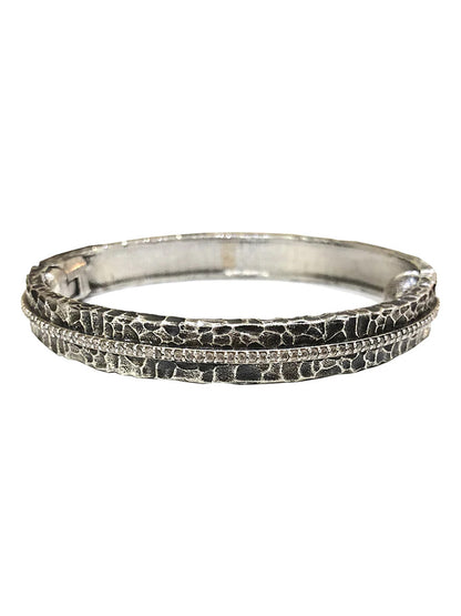 Tat2 Designs Egy Crystal Line Bangle in Vintage Silver features a raised, cracked pattern accented by a fine line of sparkling Cubic Zirconia through the center and is finished with a secure magnetic hinge closure.