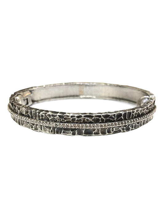 Tat2 Designs Egy Crystal Line Bangle in Vintage Silver features a raised, cracked pattern accented by a fine line of sparkling Cubic Zirconia through the center and is finished with a secure magnetic hinge closure.