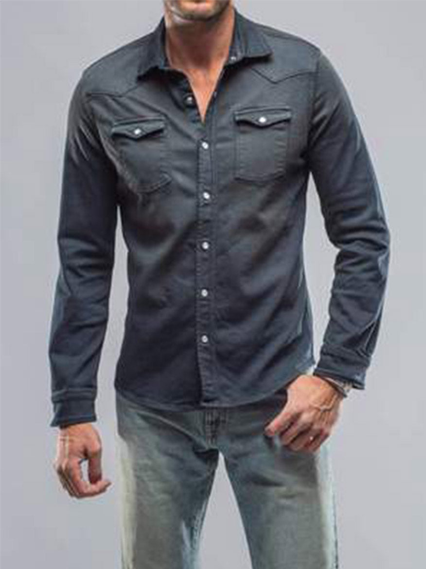 A man wearing the Teleria Zed Roper Western Snap Shirt in Anthracite, paired with light jeans, stands against a plain background, exuding subtle Western inspiration.