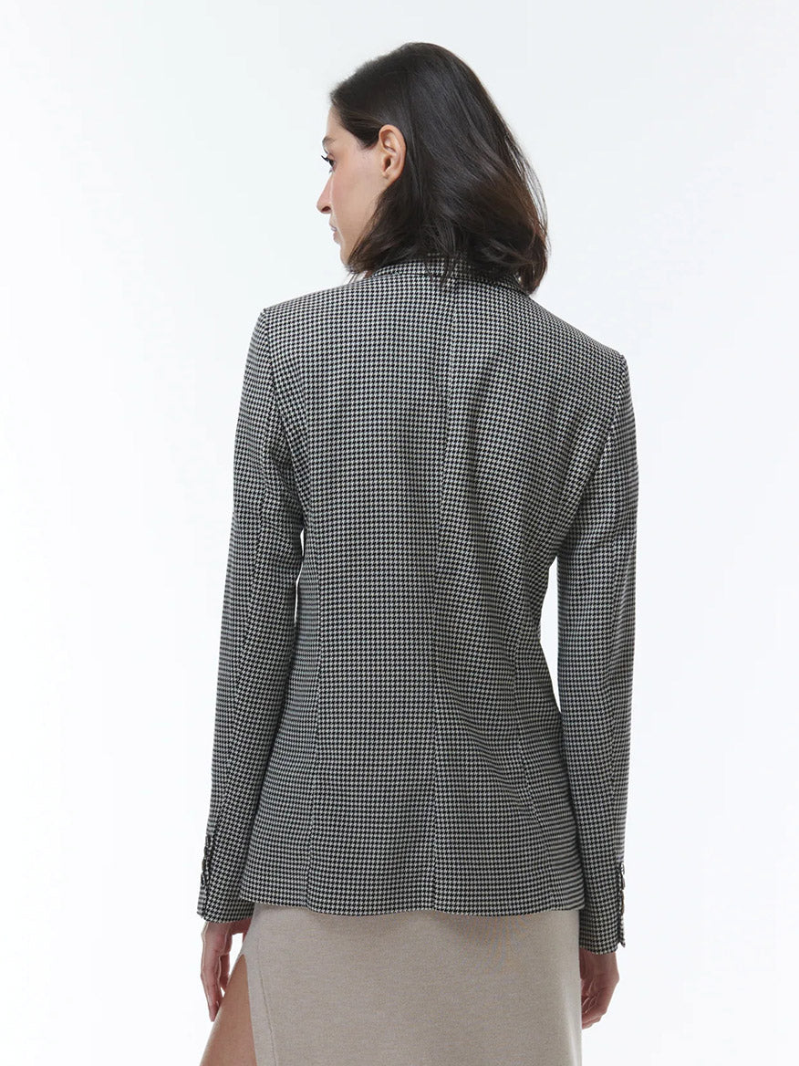 A woman from behind wearing a THEO The Label Eris Baby Houndstooth Blazer in Black/Ivory and a beige skirt.