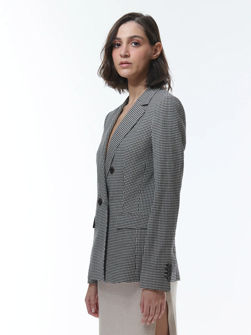 A fashion-forward individual wearing THEO The Label Eris Baby Houndstooth Blazer in Black/Ivory stands against a white background.