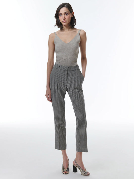A woman wearing a sleeveless v-neck top and THEO The Label Eris Baby Houndstooth Pant in Black/Ivory against a white background.