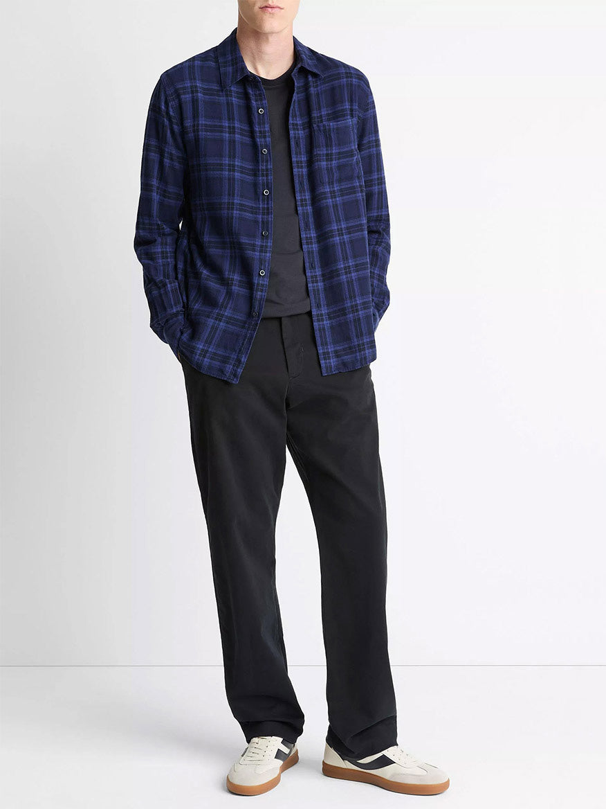 A person stands against a plain background wearing the Vince Big Horn Plaid Cotton Button-Front Shirt in Monarch Combo over a black t-shirt, black pants, and white sneakers with gum soles.