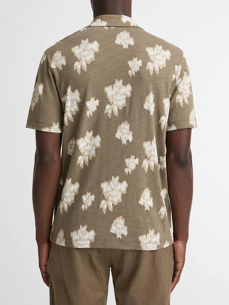 A person is seen from the back wearing the Vince Blurred Roses Short-Sleeve Button-Front Shirt in Kalamata Combo, featuring a brown base with a light floral pattern, standing against a plain background.