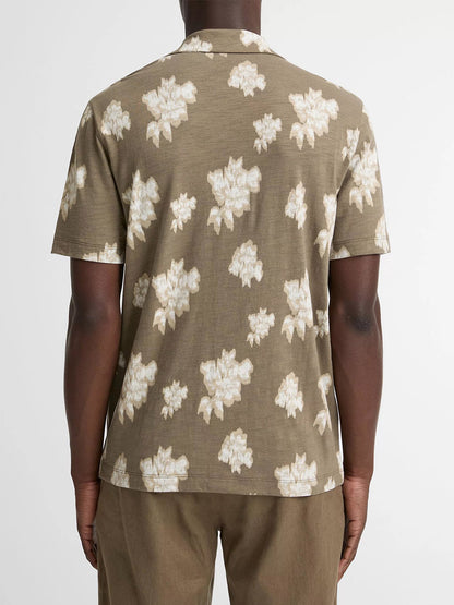 A person is seen from the back wearing the Vince Blurred Roses Short-Sleeve Button-Front Shirt in Kalamata Combo, featuring a brown base with a light floral pattern, standing against a plain background.