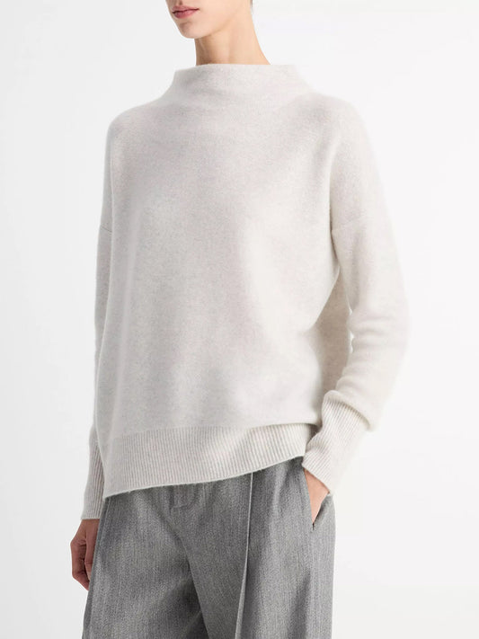 A person wears the Vince Plush Cashmere Funnel-Neck Sweater in Heather Platinum and gray pants, standing against a plain white background.
