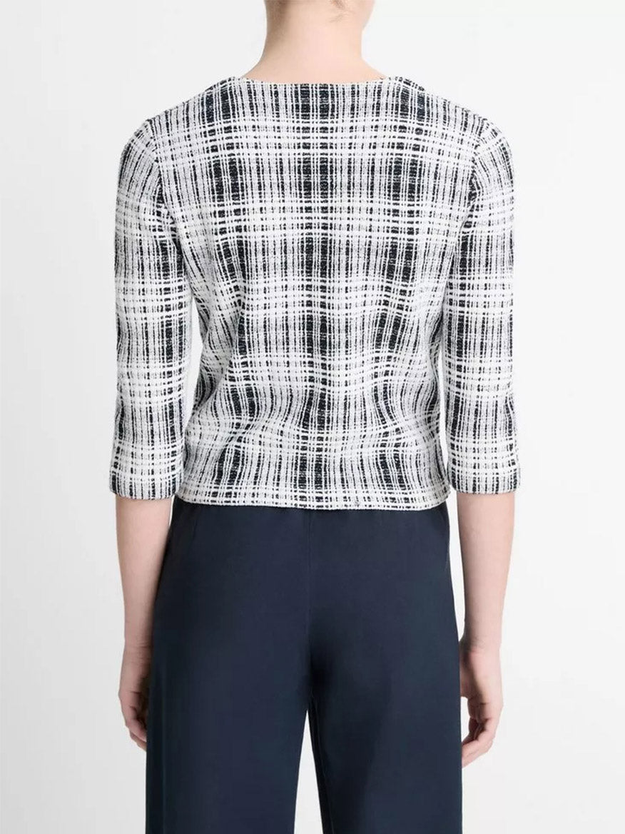 A figure in Vince's Coastal Blue/Off-White Bouclé Plaid Cotton-Blend Elbow-Sleeve Sweater and dark pants is seen from behind, highlighting the intricate plaid on the sleeves.