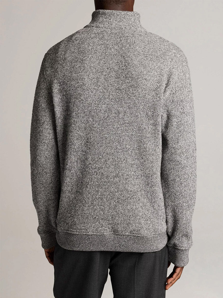 A person is shown from shoulders to hips wearing the Vince Brushed Cotton-Blend Waffle Quarter-Zip Pullover in Heather Black, paired with dark pants against a plain light background.