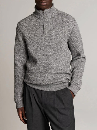 Person wears the Vince Brushed Cotton-Blend Waffle Quarter-Zip Pullover in Heather Black and dark gray trousers, standing with one hand in pocket against a plain background.