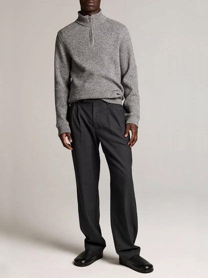 A person wears the Vince Brushed Cotton-Blend Waffle Quarter-Zip Pullover in Heather Black, paired with dark pleated trousers and black shoes against a plain light background.