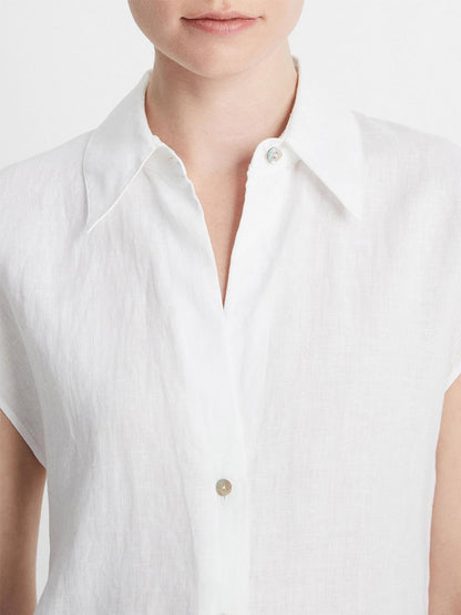 Close-up of a person wearing a Vince Linen Cap-Sleeve Button-Front Blouse in Optic White. Their face is not fully visible and their lips are closed.