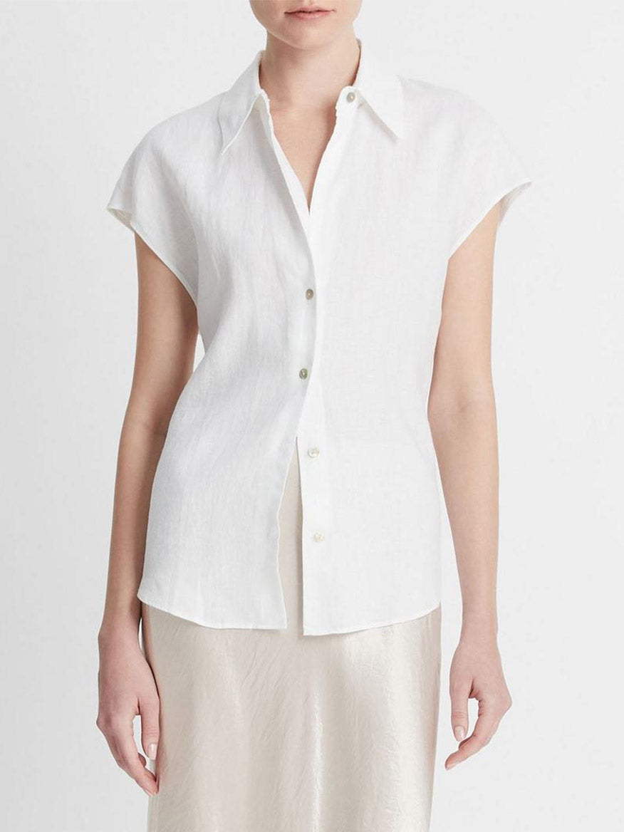 A person is wearing a Vince Linen Cap-Sleeve Button-Front Blouse in Optic White, paired with a light-colored satin skirt.