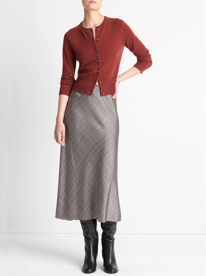 A person wears the Vince Metal-Button Wool & Cashmere-Blend Cardigan in Siena (rust), a grey plaid midi skirt, and black knee-high boots, standing against a plain white background.
