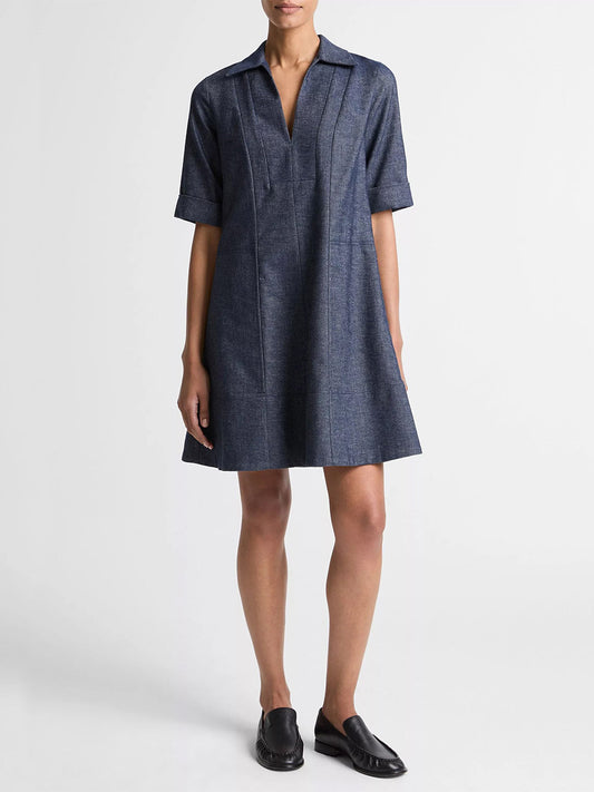 A person wearing the Vince Cotton-Linen Chambray A-Line Dress in Indigo stands against a plain white background, paired with black slip-on shoes.