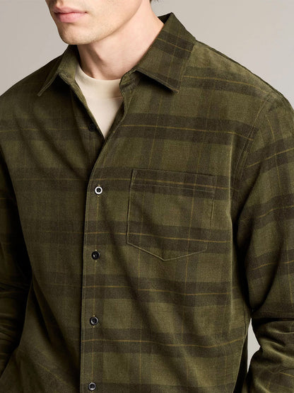 A man wears a Vince Hamilton Plaid Cotton Corduroy Button-Front Shirt in Night Leaf Combo over a beige top, shown from shoulders to waist, facing slightly left.