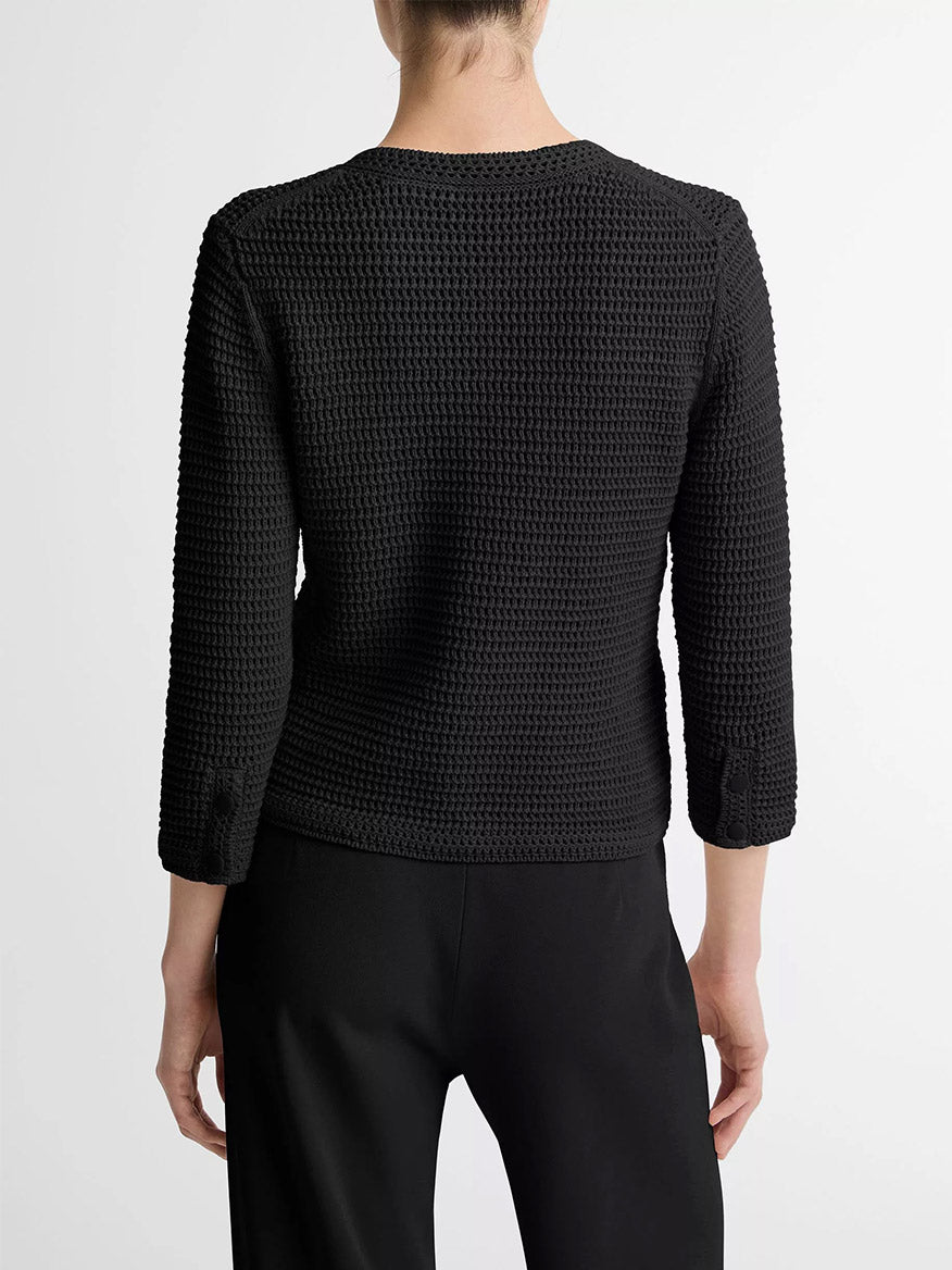 A person is seen from the back wearing the Vince Italian Cotton Crochet Cardigan in Black with matching black pants against a plain light background, ideal for effortless spring layering.