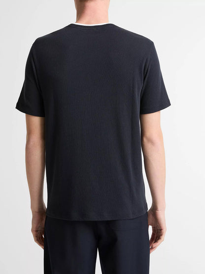 A person stands facing away from the camera, wearing the Vince Cotton Double-Collar T-Shirt in Coastal Blue/Optic White and black pants against a white background.