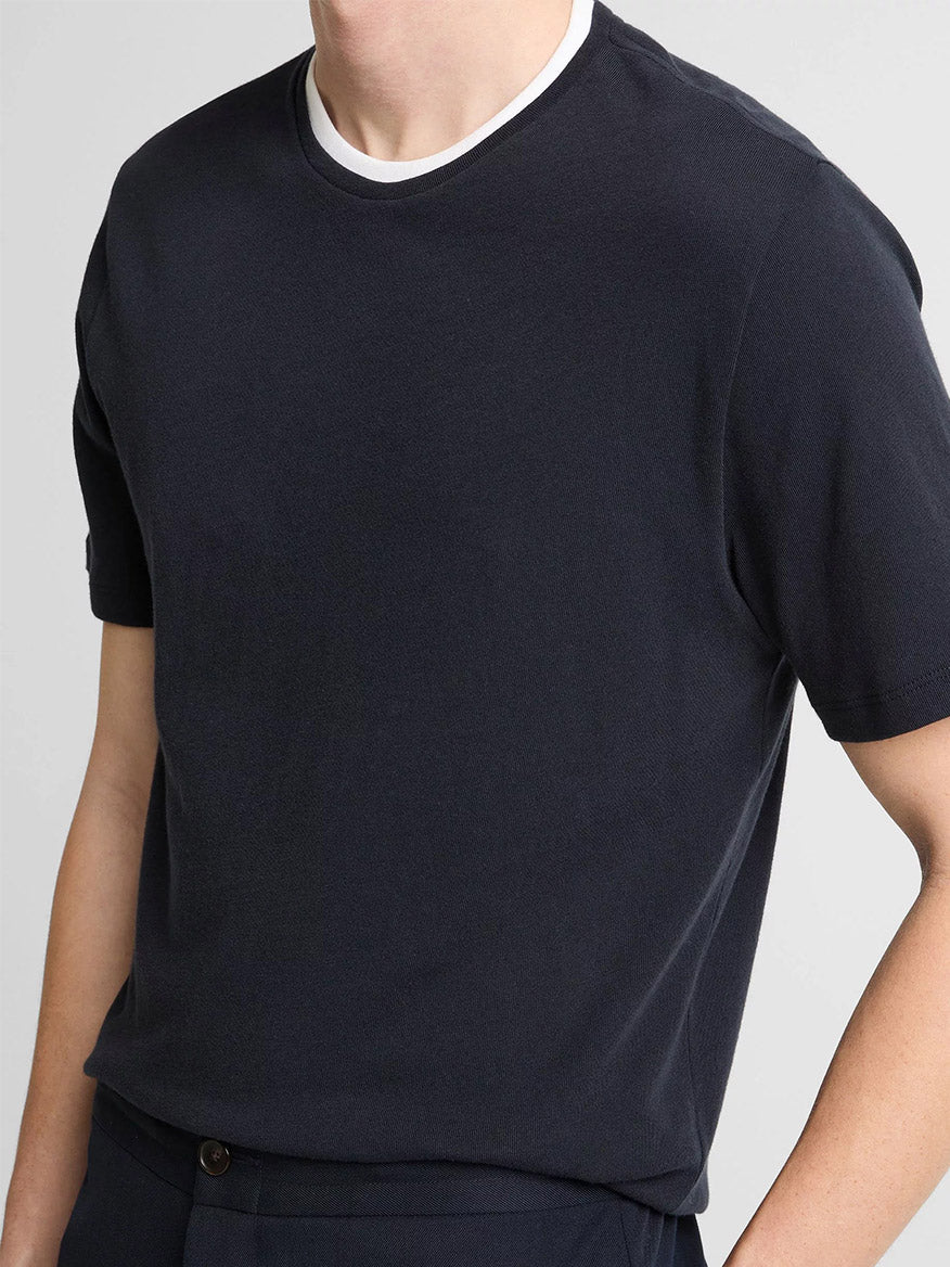 Someone wearing the Vince Cotton Double-Collar T-Shirt in Coastal Blue/Optic White, layered for a modern look with dark pants, shown from shoulders to hips.