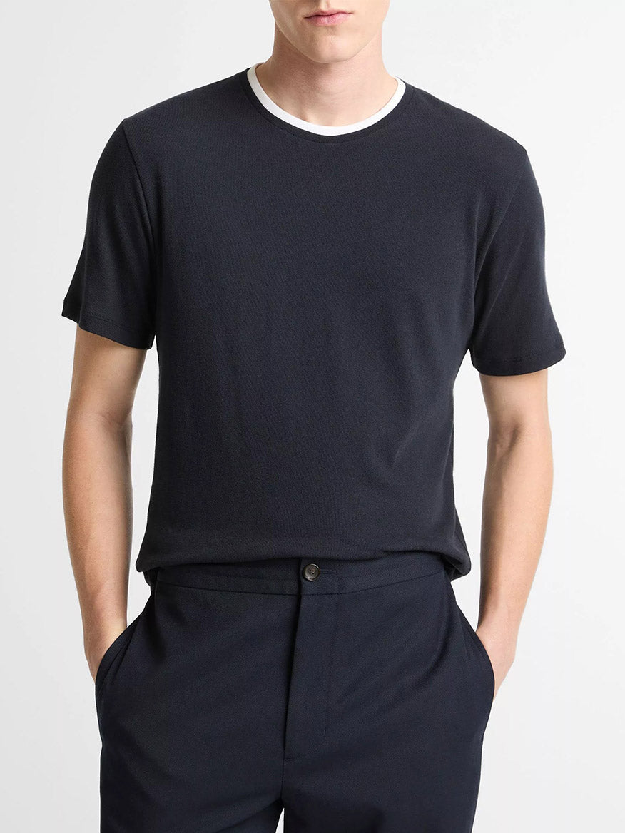 Man wearing a Vince Cotton Double-Collar T-Shirt in Coastal Blue/Optic White—short-sleeve with a layered crew neck—paired with black trousers, standing hands-in-pockets against a plain background.