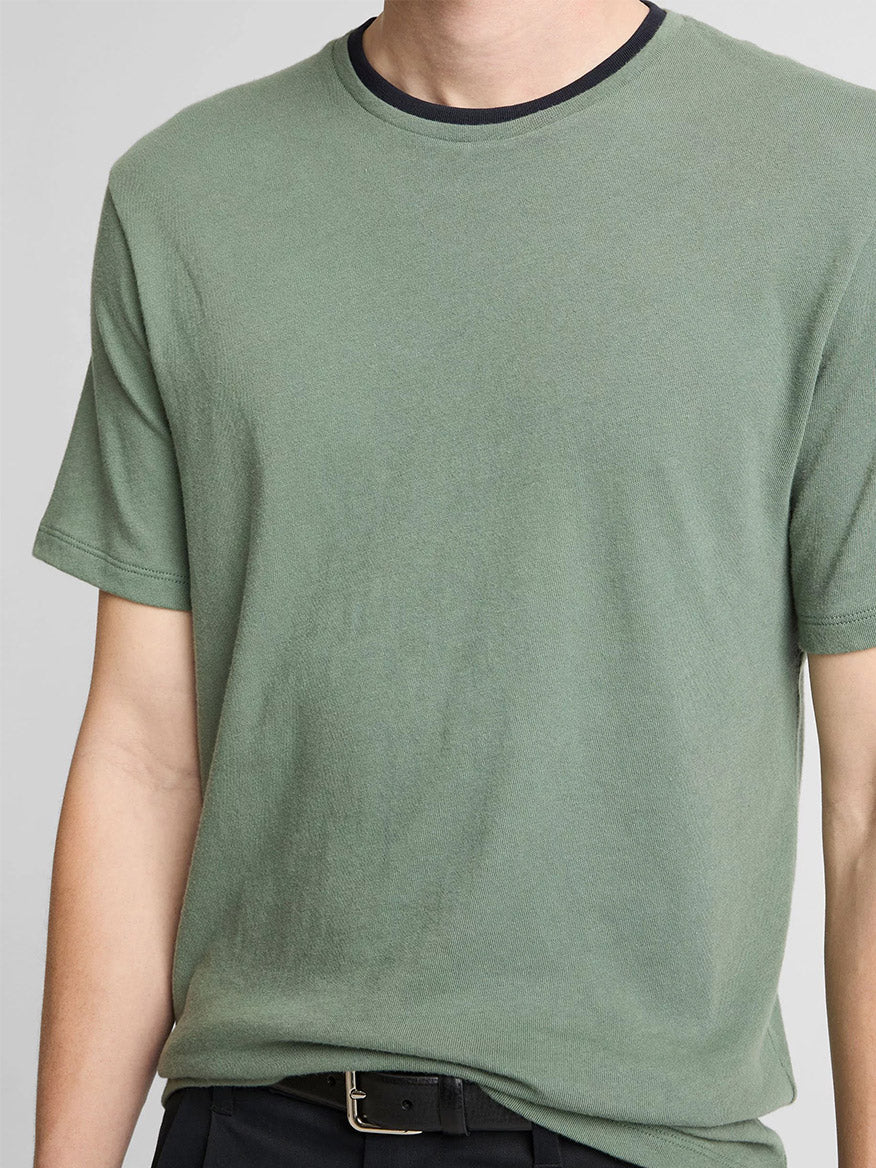 A person is shown from shoulders to waist wearing the Vince Cotton Double-Collar T-Shirt in Laurel/Coastal Blue and black pants.
