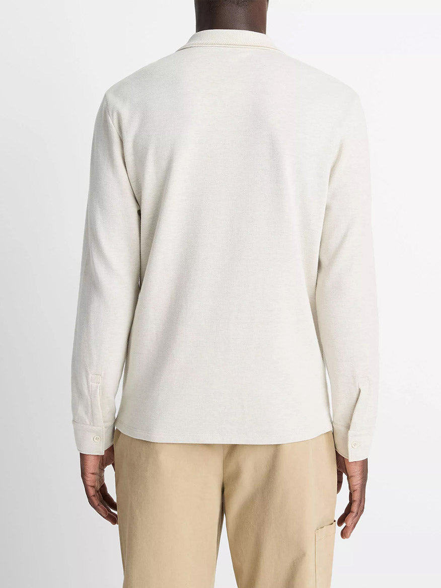A person wearing a Vince Heathered Double-Face Cotton-Blend Polo Shirt in Heather Blanco/Terrapin and beige pants stands facing away from the camera against a plain background.