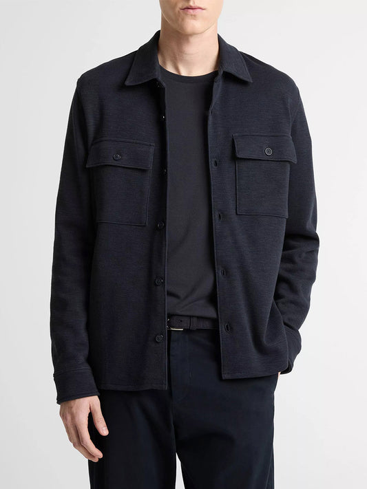 A person wearing a Vince Double-Slub Cotton-Blend Shirt Jacket in Coastal Blue, layered over a black t-shirt and black pants, stands against a plain light background.