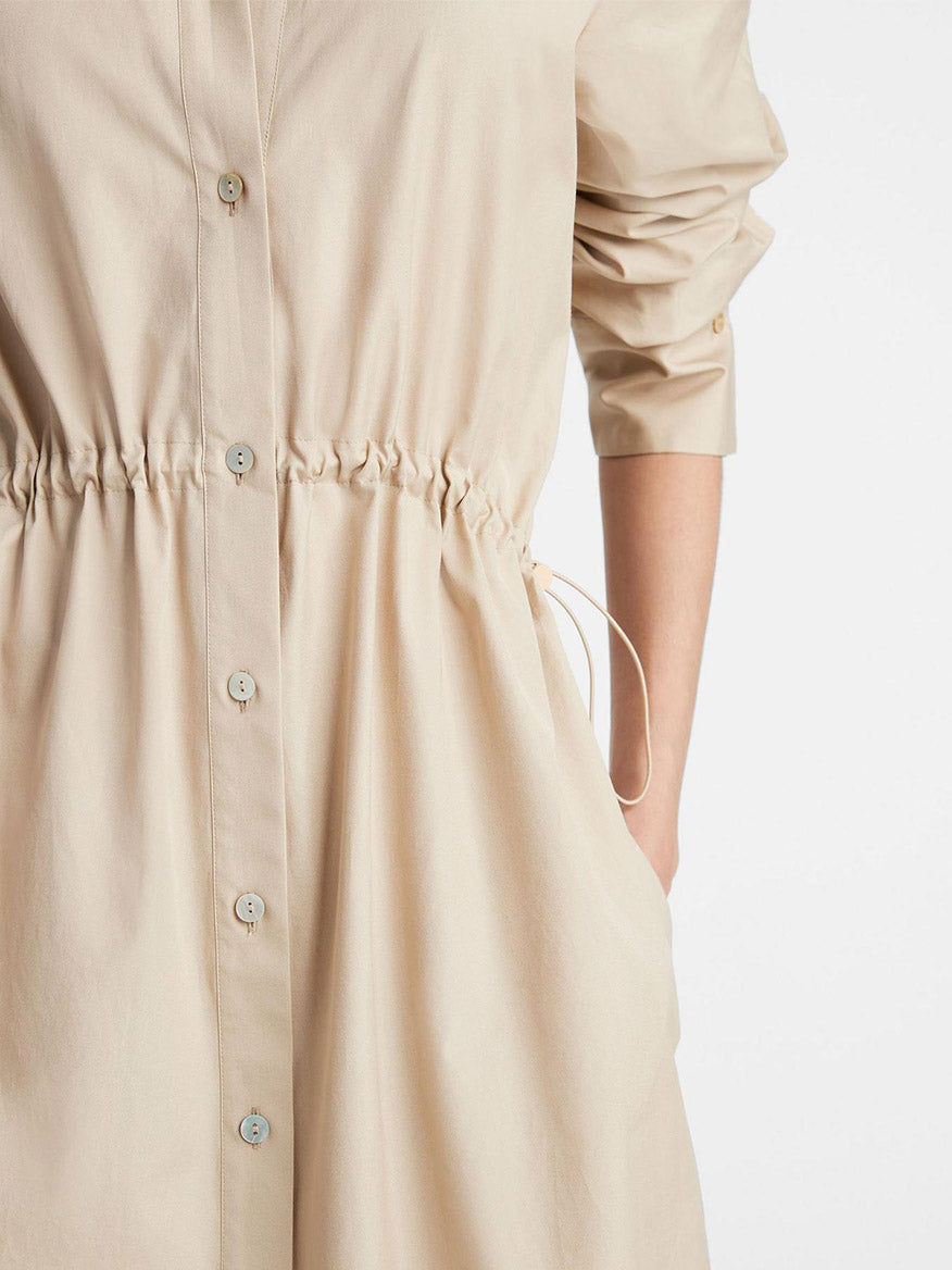 Close-up of a Vince Cotton Drawcord Ruched Shirt Dress in White Oak with button-front closure and cinched drawcord waist, emphasizing the fabric texture and stitching.