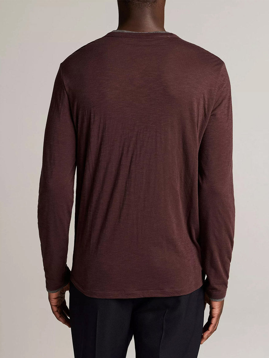 A person faces away from the camera, wearing the Vince Slub Pima Cotton Double-Layer T-Shirt in Chocolate Plum/Medium Heather Grey with black pants.