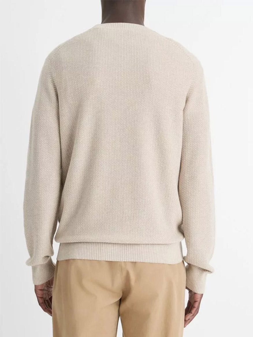 A person is seen from behind wearing a Vince Geo-Jacquard Wool-Blend Crew Neck Sweater in British Khaki/Classic Cream paired with tan pants against a plain background.