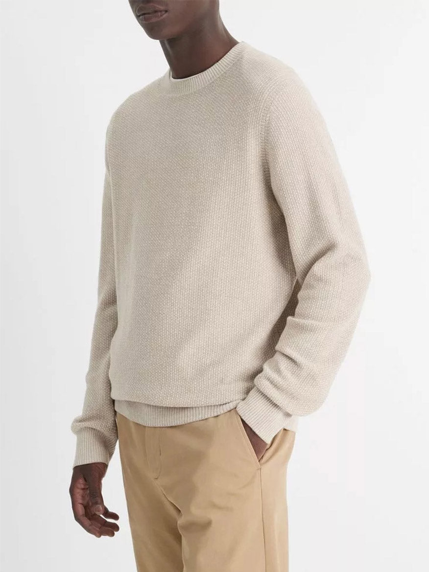 A person wearing the Vince Geo-Jacquard Wool-Blend Crew Neck Sweater in British Khaki/Classic Cream and tan pants stands against a plain white background.