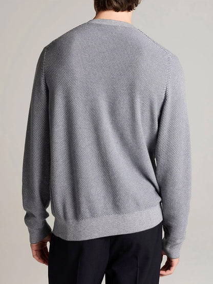 Wearing the Vince Geo-Jacquard Wool-Blend Crew Neck Sweater in Late Evening/Classic Cream—a textured light gray knit crafted from a wool-cotton-cashmere blend—and black pants, the person is shown from the back against a plain background.