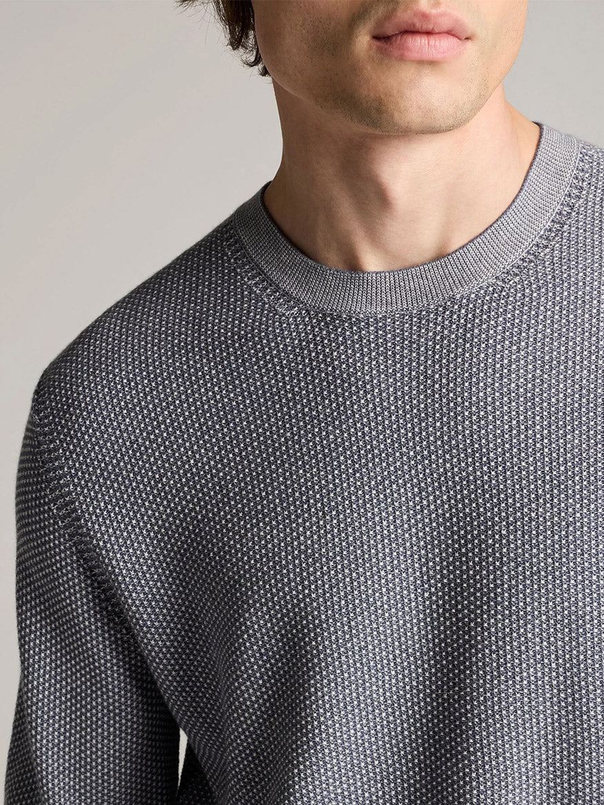 A person wearing the Vince Geo-Jacquard Wool-Blend Crew Neck Sweater in Late Evening/Classic Cream, shown from the shoulders up with part of the face visible.