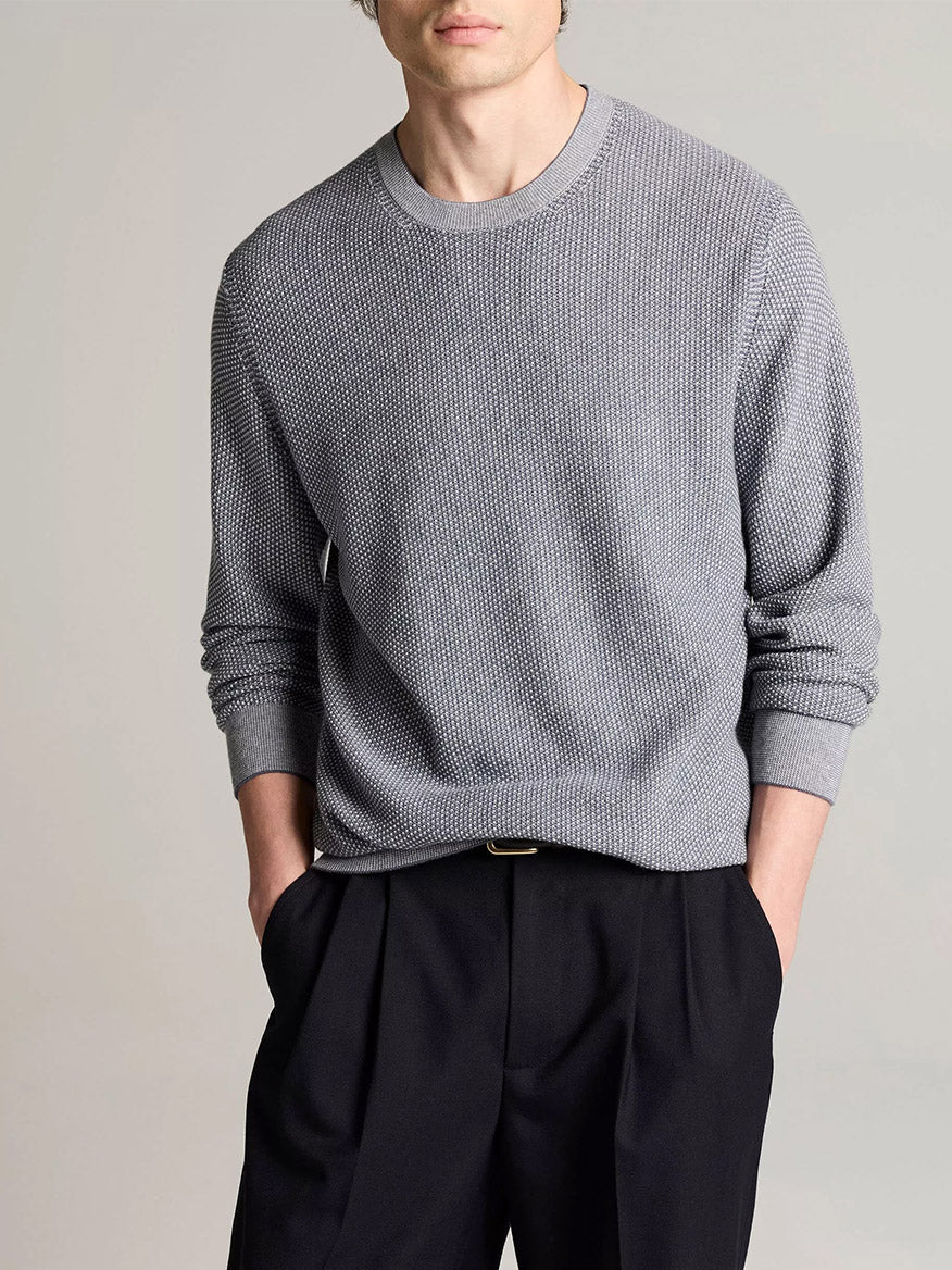 Wearing the Vince Geo-Jacquard Wool-Blend Crew Neck Sweater in Late Evening/Classic Cream and black trousers, a person stands with hands in pockets against a plain background.