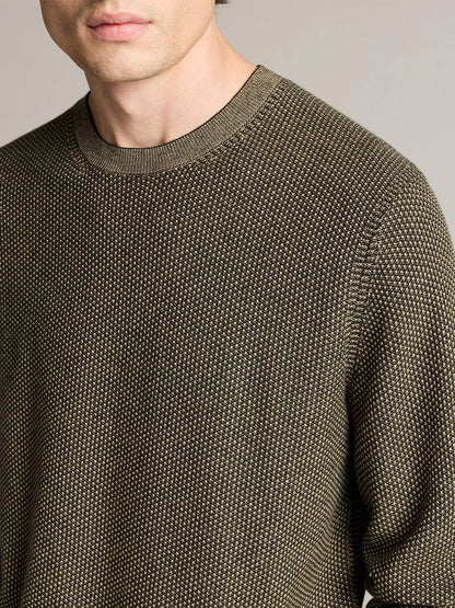 A person wears the Vince Geo-Jacquard Wool-Blend Crew Neck Sweater in Midnight Garden/River Sand, crafted from a luxurious blend of wool, cotton, and cashmere. The image is cropped at the mouth, shoulders, and mid-arm to highlight the sweater’s intricate jacquard pattern.