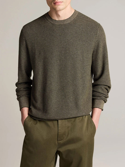 A man stands with his hands in his pockets against a plain background, wearing the Vince Geo-Jacquard Wool-Blend Crew Neck Sweater in Midnight Garden/River Sand, paired with matching pants.