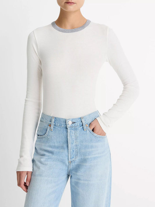 Model wears the Vince Tipped Heathered Pima Cotton-Blend Long-Sleeve T-Shirt in Off White Combo with light blue high-waisted jeans, standing against a plain white background.