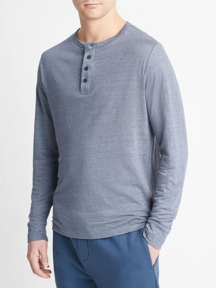 Man wearing a Vince Linen Long Sleeve Henley in Washed Indigo with button detailing, paired with blue trousers.