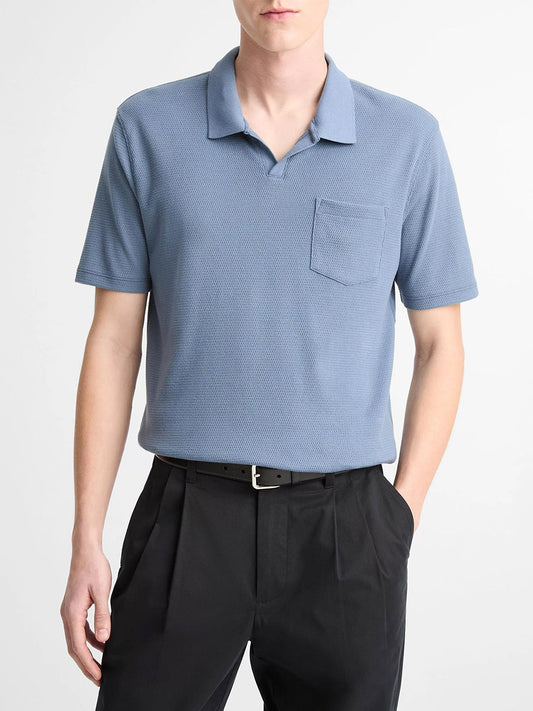A person is wearing the Vince Johnny Collar Polo Shirt in Uniform Blue, tucked into black trousers with a belt, standing against a plain background.