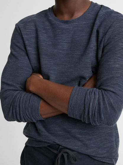 Person wearing the Vince Double-Knit Cotton-Blend Long-Sleeve Shirt in Heather Coastal Blue, arms crossed and photographed from shoulders to waist against a neutral background.