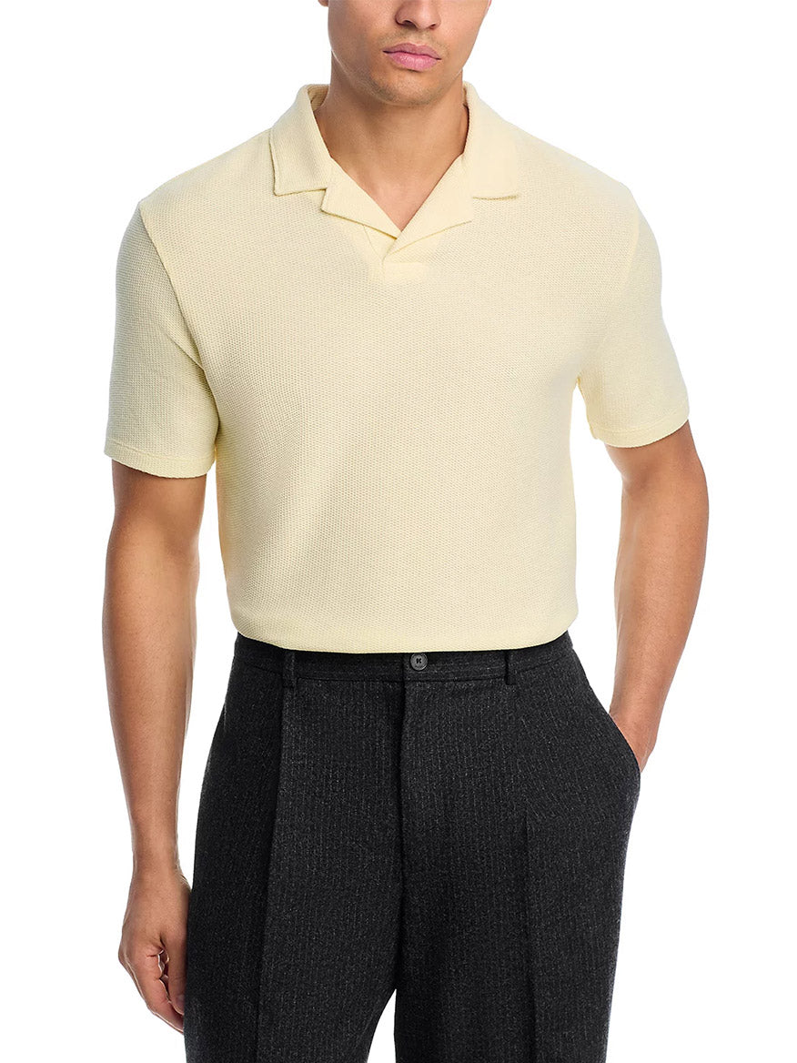 A man wears the Vince Macro Honeycomb Cabana Johnny Collar Shirt in Cream paired with dark gray dress pants, standing with one hand in his pocket.